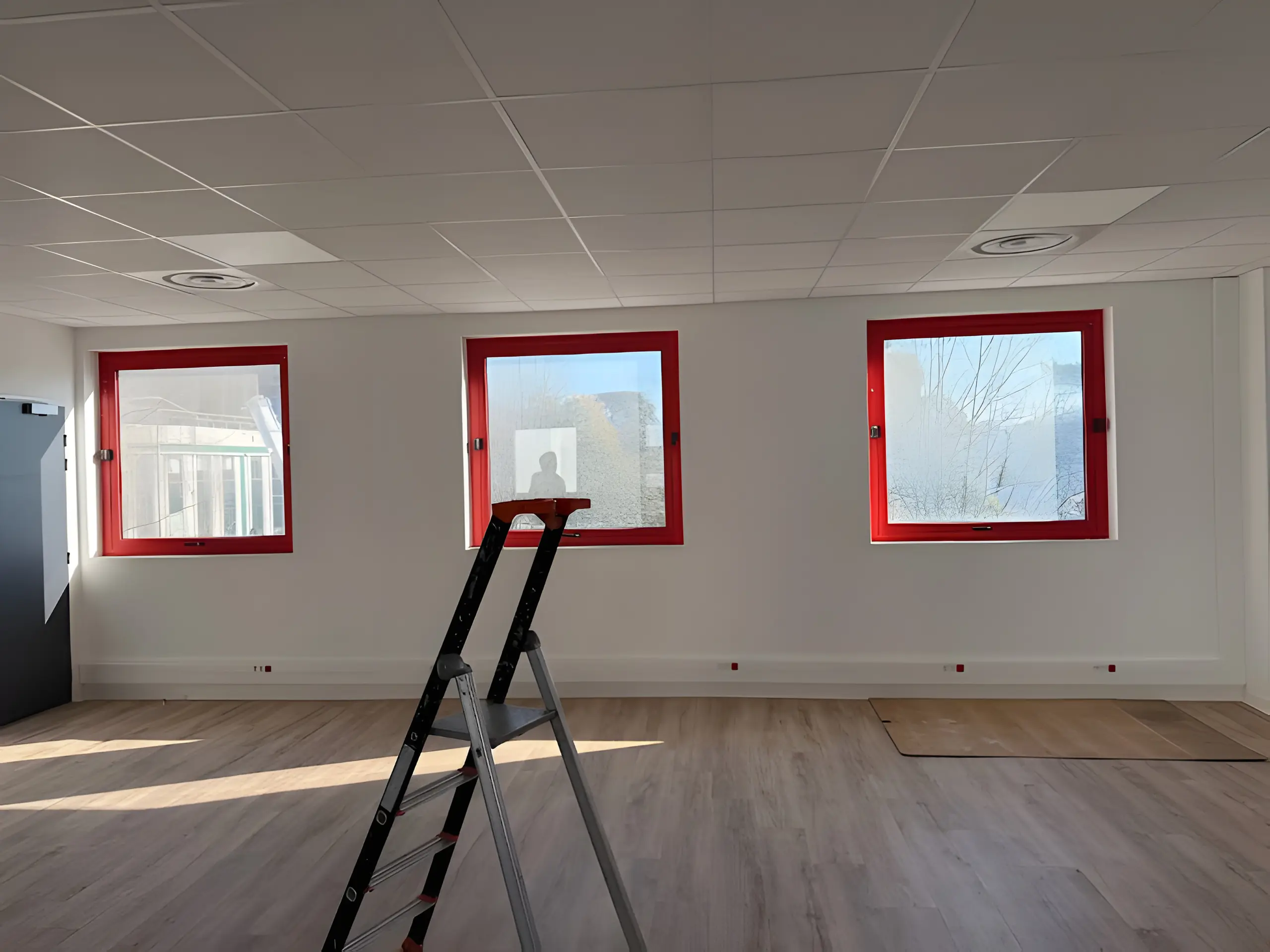 Plateau de bureaux : trois fenêtres à cadre rouge posées, sol fini