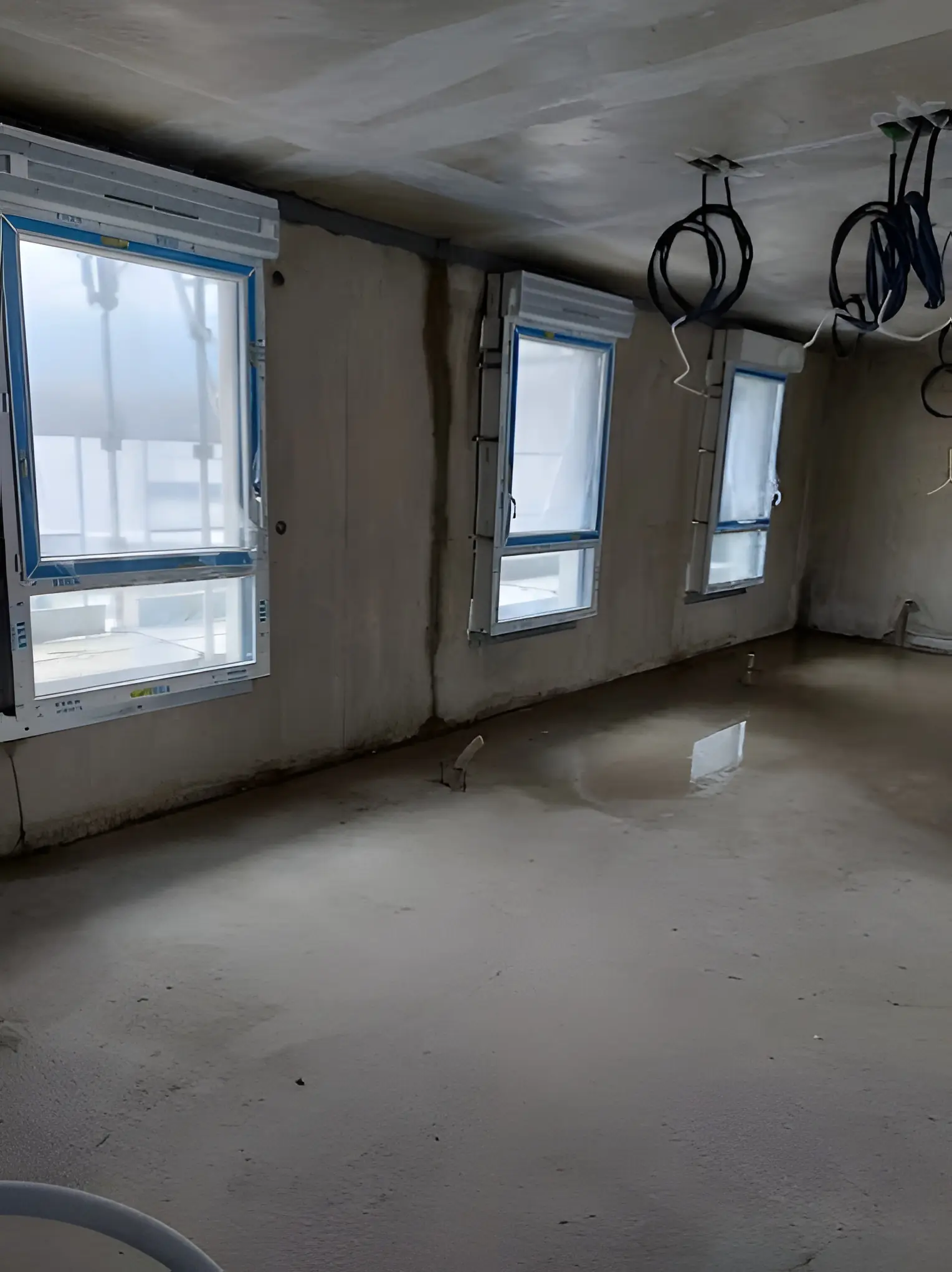 Pièce brute d’un immeuble en chantier : fenêtres blanches neuves posées dans les murs en béton